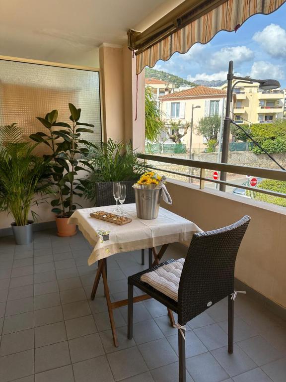 a table and chair on a balcony with a window at Studio grande terrasse 2 min plage & commerces in Roquebrune-Cap-Martin