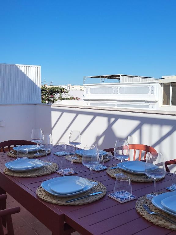a wooden table with plates and wine glasses on it at Villa Graça Olhão in Olhão