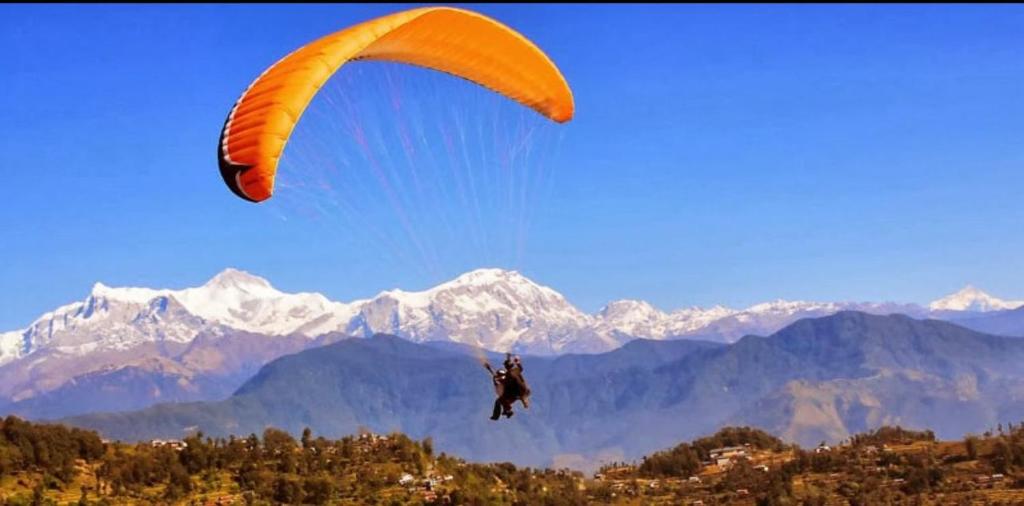 a person riding a paraglider in the sky over mountains at Sultan Resorts 7 star Luxurious accommodations 