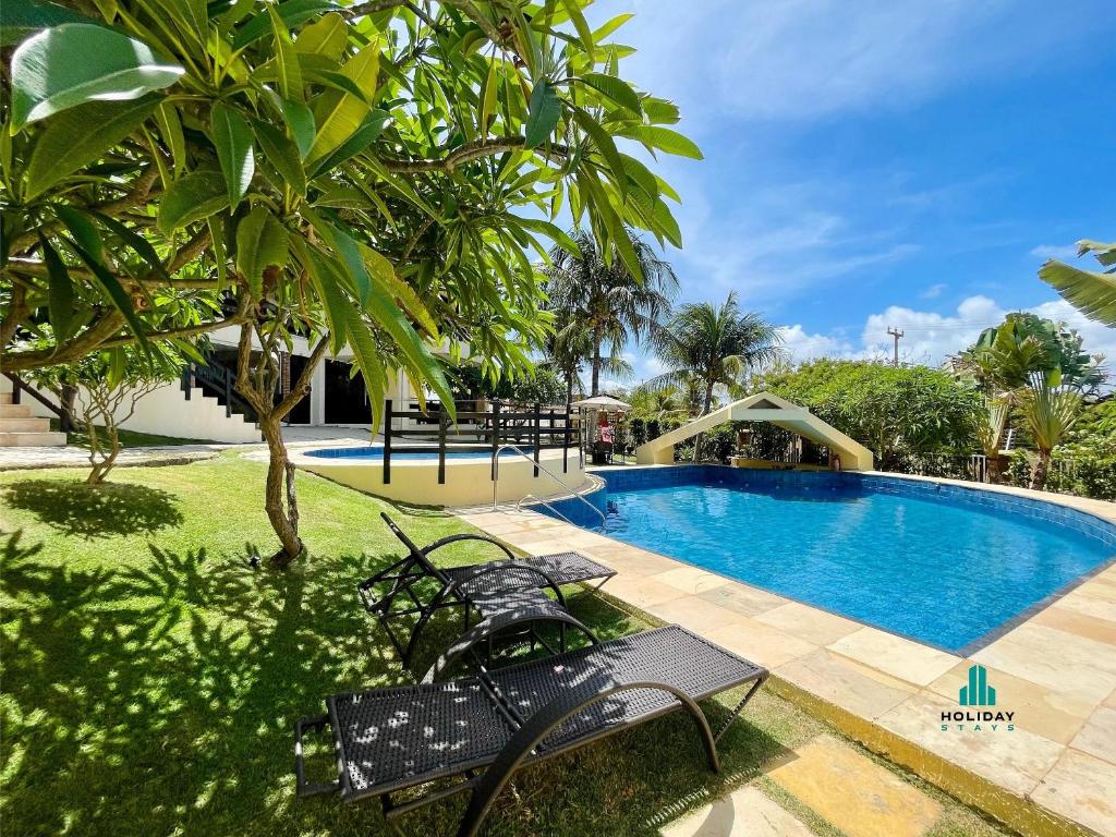 MangabeiraDunnas XXI By Holiday Stays的一座游泳池,旁边是树,设有两个长椅