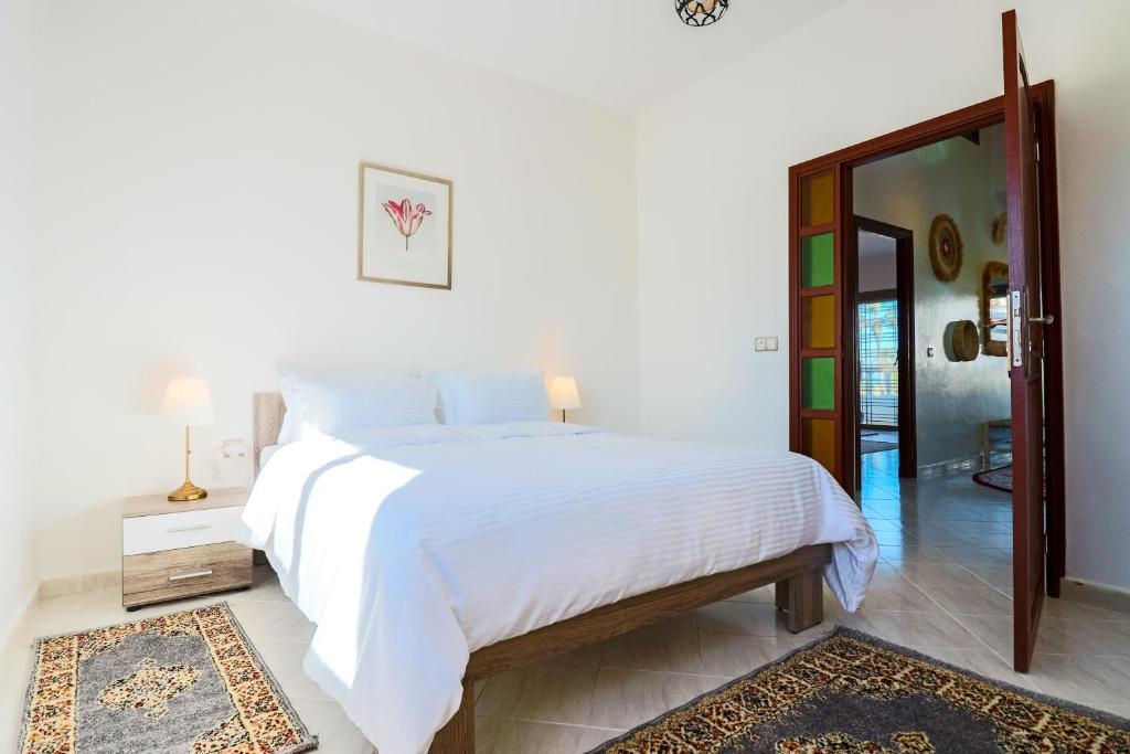 ein Schlafzimmer mit einem großen weißen Bett und einem Spiegel in der Unterkunft L'Eden d'Elynia Villa de Luxe avec piscine et front de mer in Rabat