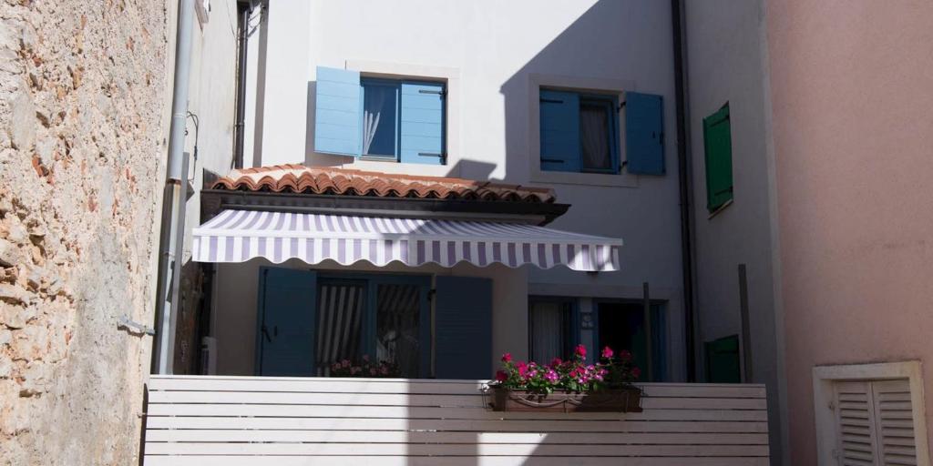 a building with two windows and a balcony with flowers at Pinea in Veli Lošinj