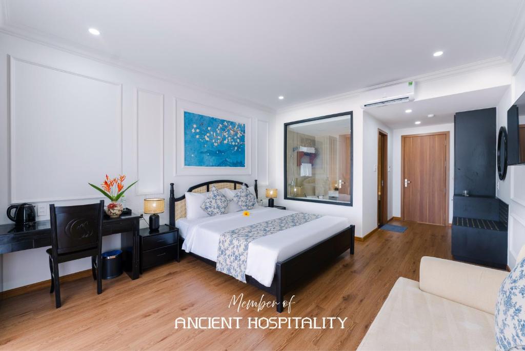 a bedroom with a bed and a desk in a room at Ancient Beach Boutique & Spa - Beachfront Hotel in Hoi An