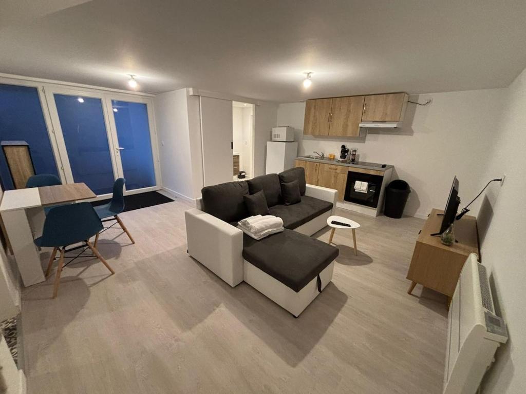 ein Wohnzimmer mit Couch und Tisch und eine Küche in der Unterkunft Le Breakaway, cosy et calme in Saint-Junien