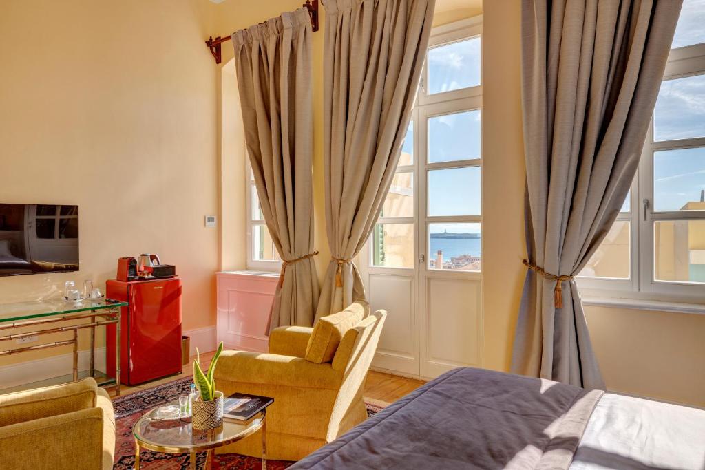 a bedroom with a bed and a chair and a window at Palazzo Santa Maria - Historic Hotels of Europe in Ermoupoli