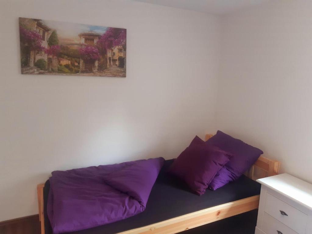 MühlthalFleischmannhof Do san ma dahoam的一张带紫色枕头的床和墙上的绘画