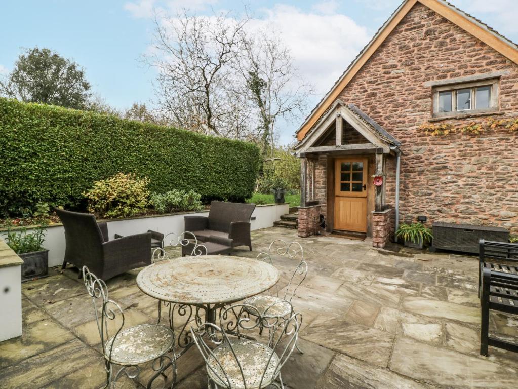 a patio with a table and chairs and a building at Walnut Cottage in Usk