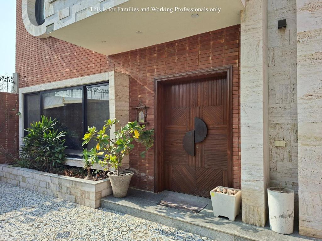 een houten deur op een bakstenen gebouw met planten bij 2 Bedroom Serviced Home in Lahore