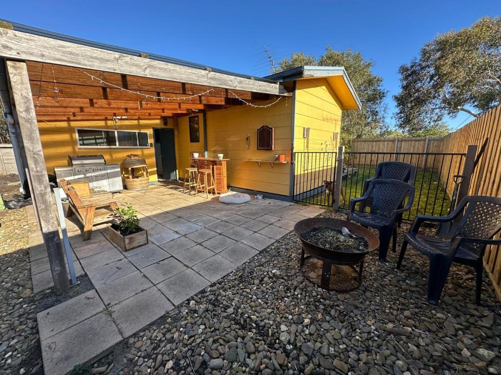 a patio with chairs and a grill and a house at South Dudley Beach House - Pet friendly in Dudley South