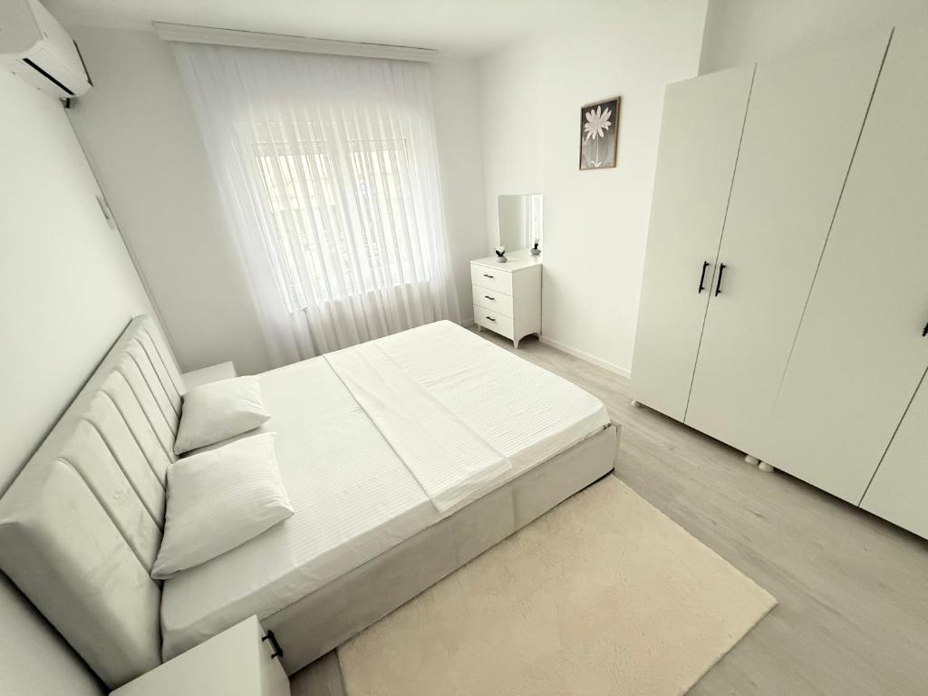 a white bedroom with a bed and a white cabinet at Rubinas Apartment in Prizren