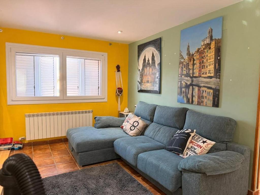 a living room with a blue couch and a window at Una casa ideal para familias o grupos de amigos in Caldes de Malavella