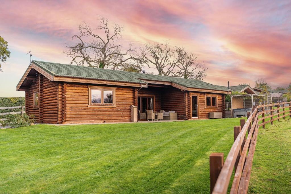 a log cabin with a green lawn in front of it at Hunters Lodge in Leyburn
