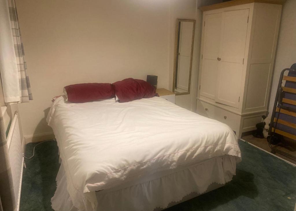 ein Schlafzimmer mit einem weißen Bett mit zwei roten Kissen in der Unterkunft Firs Drive in Cranford