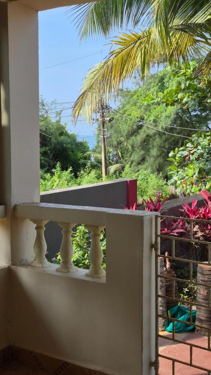 a balcony with a view of a palm tree at Ferns Cottage in Calangute