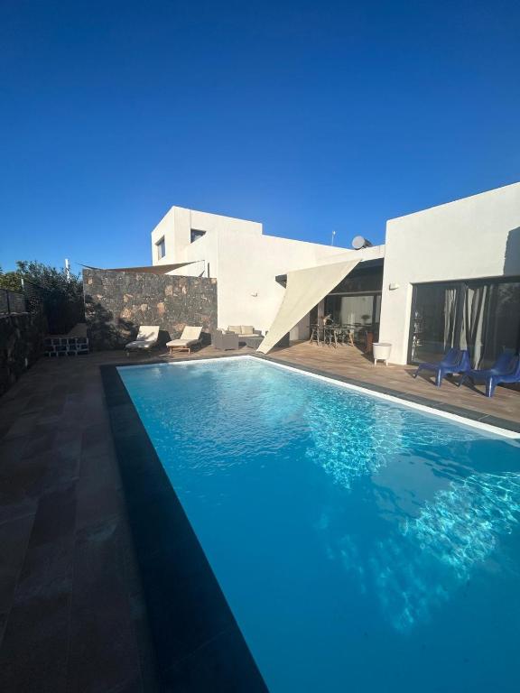 a swimming pool in front of a house at Villa Groovy in Lajares