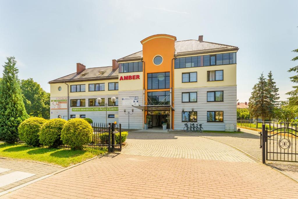 Centrum Rehabilitacyjno - Wczasowe Amber في كولوبرزيغ: مبنى ابيض كبير عليه لافته