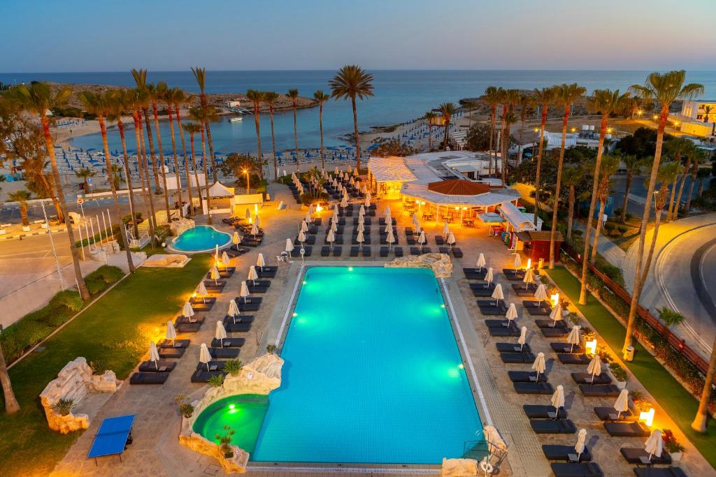 an overhead view of a swimming pool with lounge chairs and the ocean at Pavlo Napa Beach Hotel in Ayia Napa