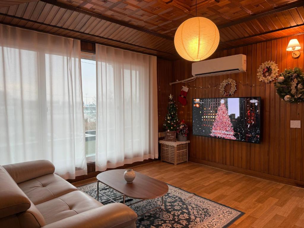 P'aengsŏngSlow Stay, Camp Humphreys的客厅配有沙发和电视上的圣诞树