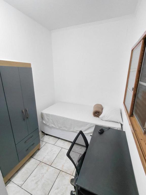 Hospedagem Residencial Butantã في ساو باولو: غرفة صغيرة بها سرير وطاولة