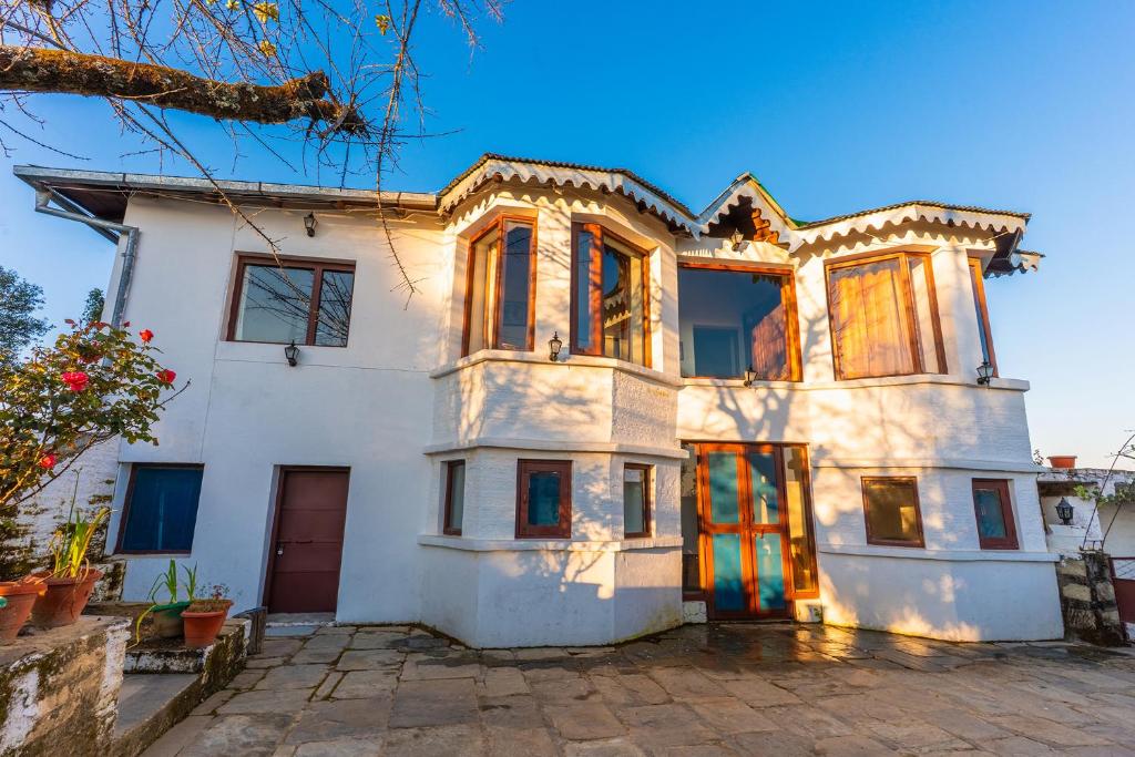 Biały dom z mnóstwem okien w obiekcie The Mukteshwar Manor w mieście Mukteshwar