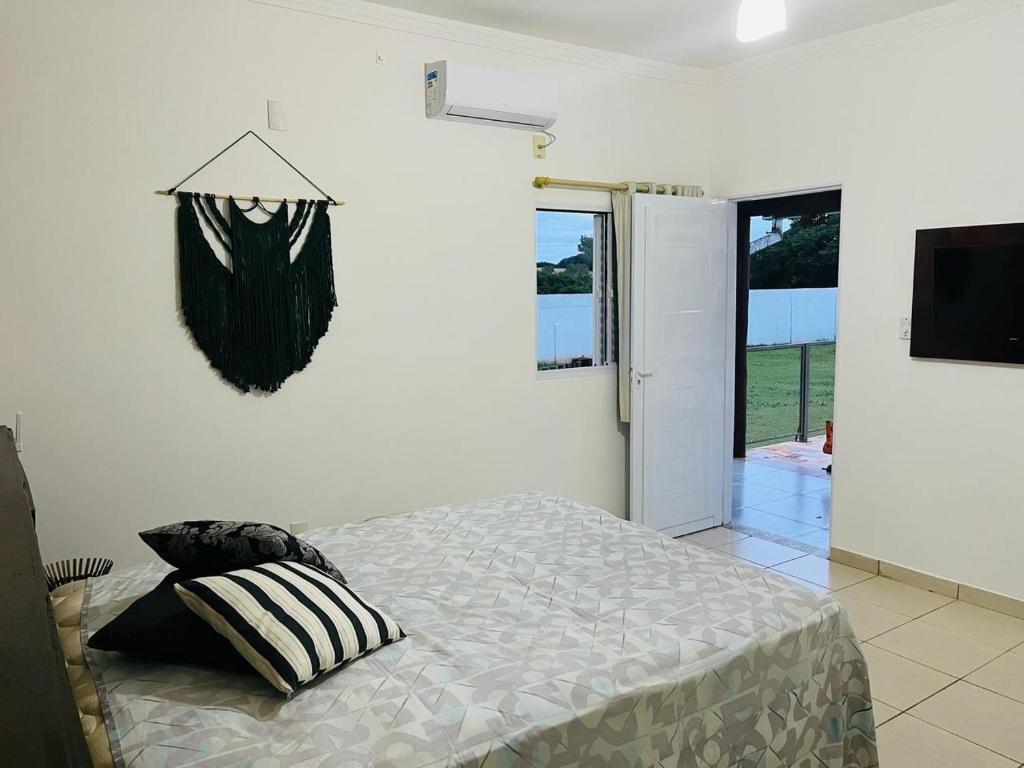 Pousada Vale Canastra في ساو جواو باتيستا دو غلوريا: غرفة نوم بيضاء فيها سرير وتلفزيون