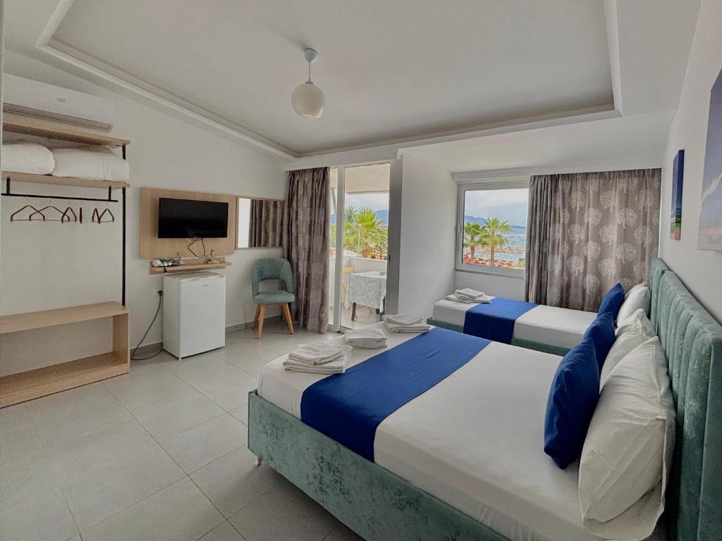 una habitación de hotel con dos camas y un escritorio en Hotel Santa Paola, en Sarandë