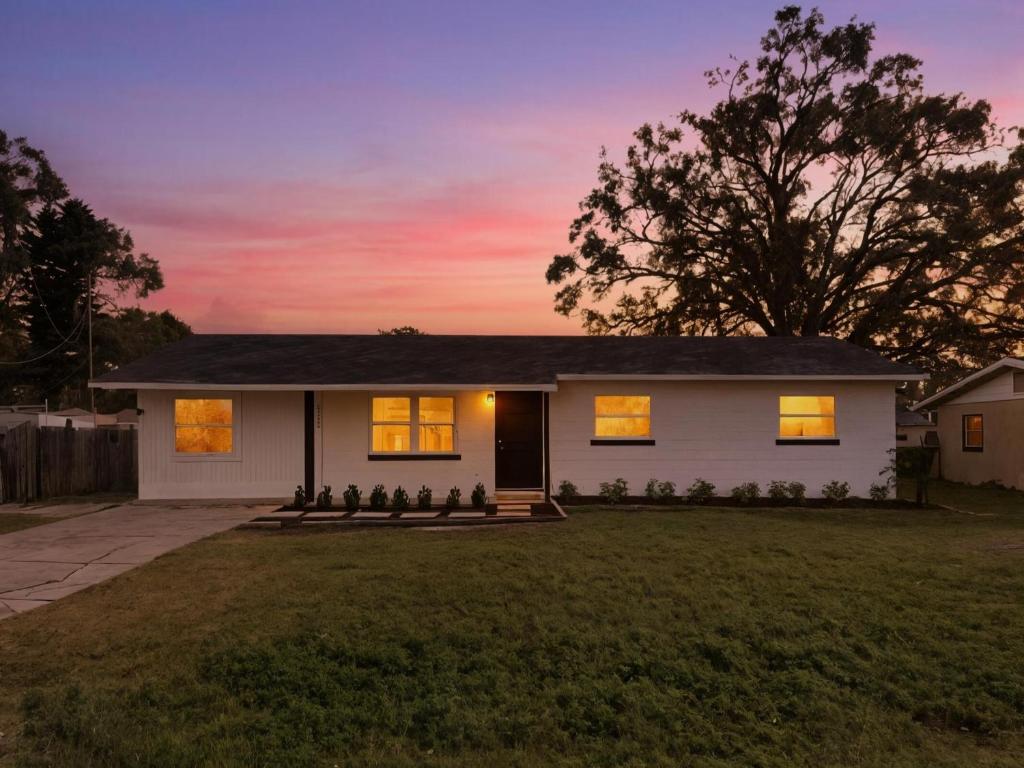 una casa bianca con un tramonto sullo sfondo di Elegant Auburndale Rooms Near the Speedway & Lake Myrtle ad Auburndale