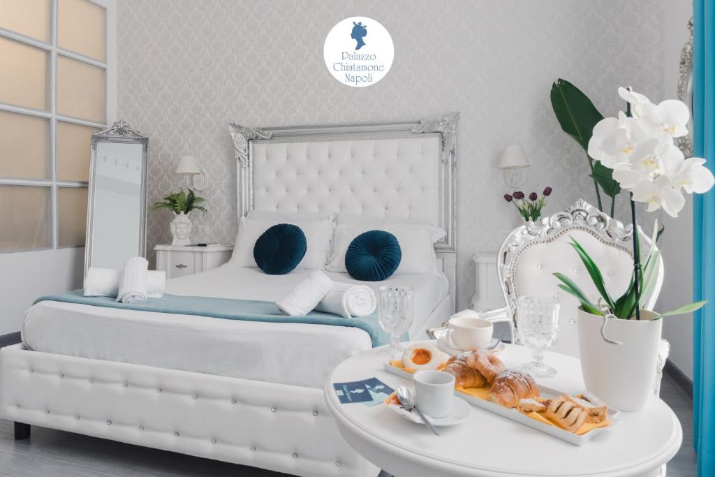 una camera da letto bianca con un letto e un vassoio di pasticcini di Palazzo Chiatamone a Napoli