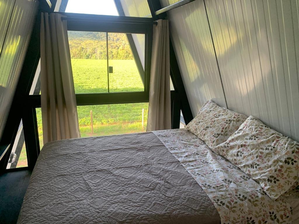 Balsa NovaにあるChalé do Cerro Fazenda Cerro do Purunaのベッドと大きな窓のある寝室