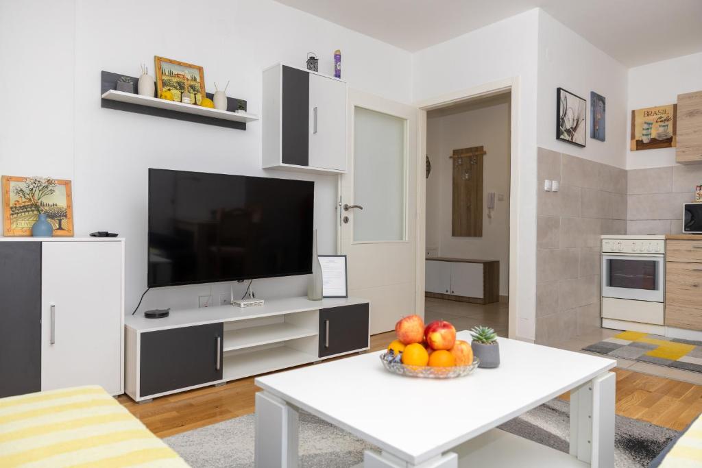 a living room with a television and a table with fruit at AVA Apartment Istočno Sarajevo in Lukavica