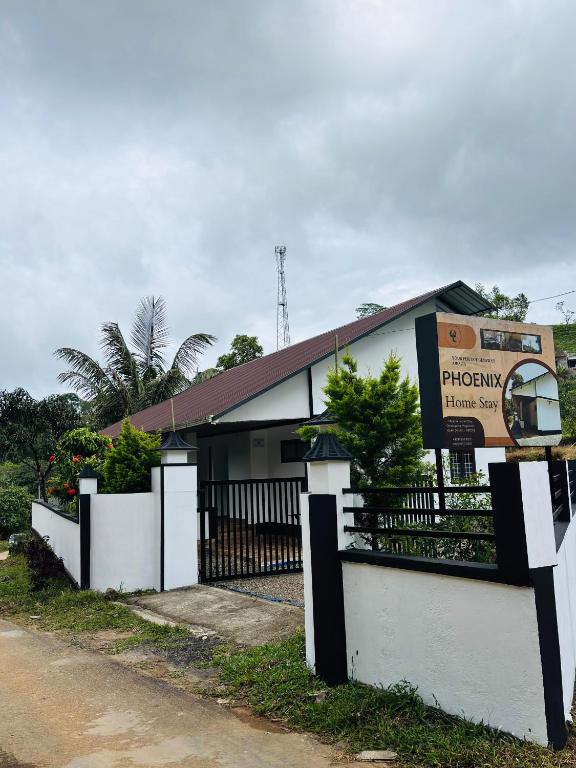 a white building with a fence and a sign at Pheonix home stay in Vagamon