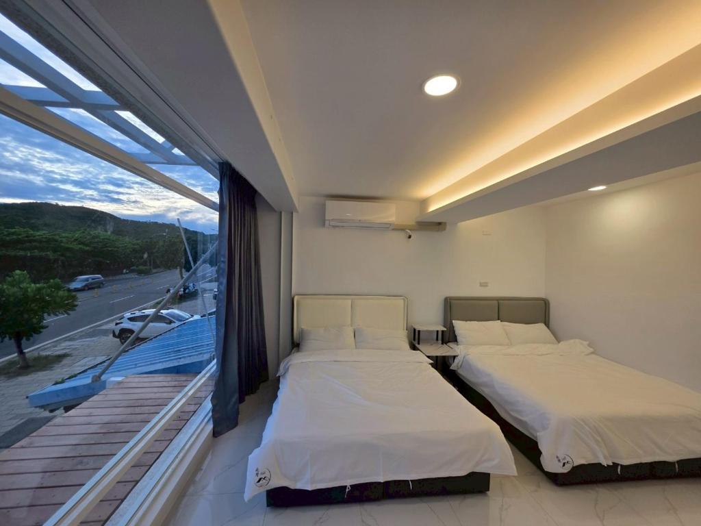 two beds in a room with a large window at Nanwan Muyang 168 Homestay in Hengchun South Gate