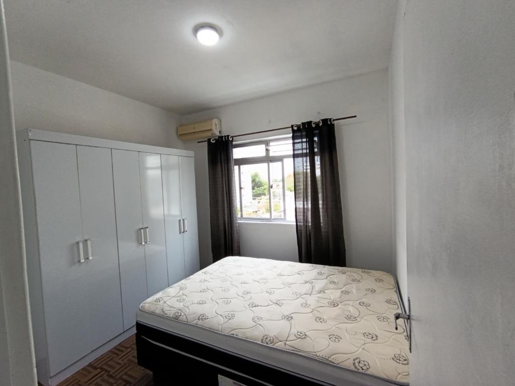 ein kleines Schlafzimmer mit einem Bett und einem Fenster in der Unterkunft AP Itajaí in Itajaí