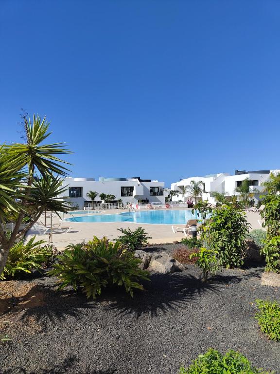 a resort swimming pool with palm trees and buildings at Casa Fuerte y Levamt in Villaverde