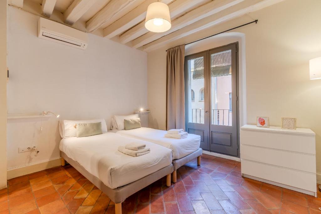 Una habitación blanca con una cama y una ventana en Flateli Ballesteries, en Girona