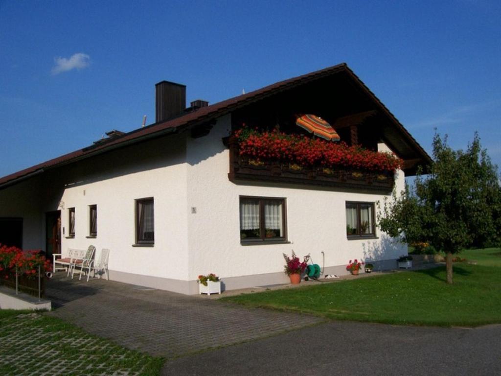 Una casa blanca con flores a un lado. en Ferienwohnung Wenzl, en Zandt