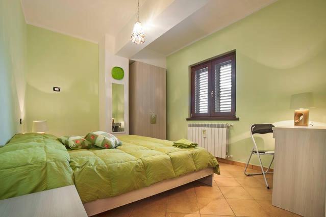 een slaapkamer met een groen bed en een bureau bij B&B La Rosa dei Venti in Acri