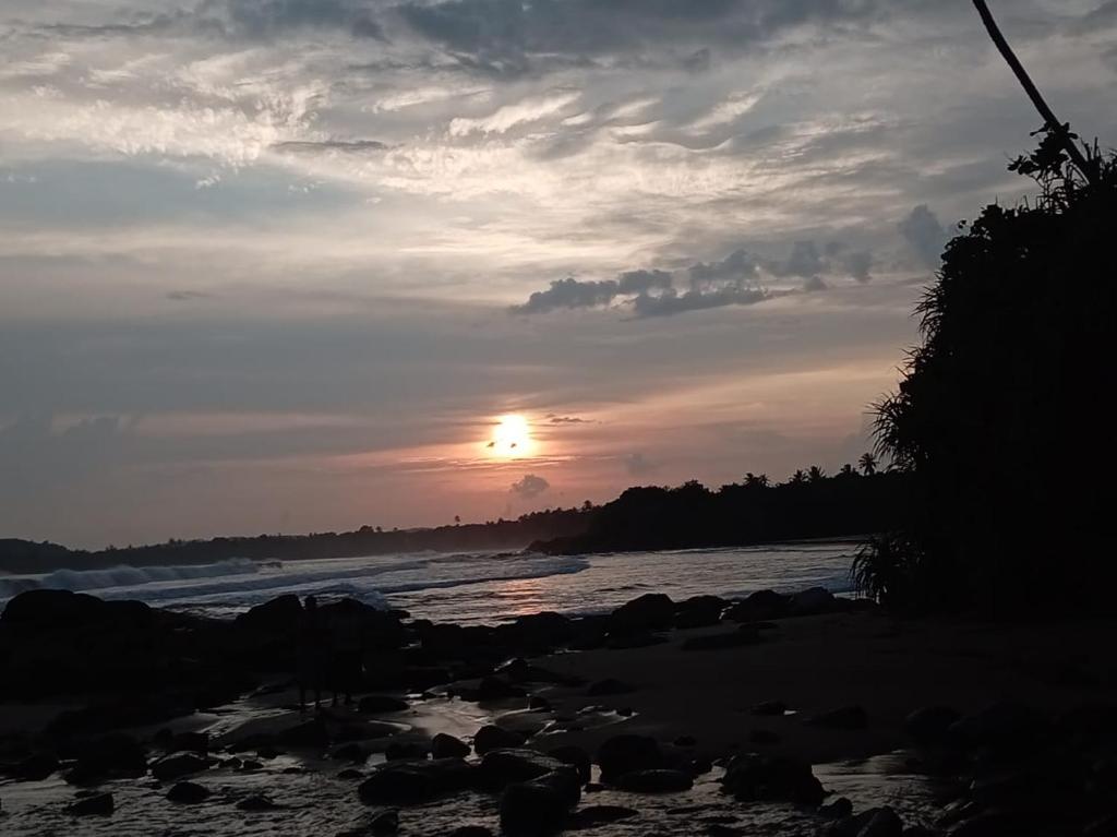 a sunset on a beach with the ocean at White shell in Sinimodera