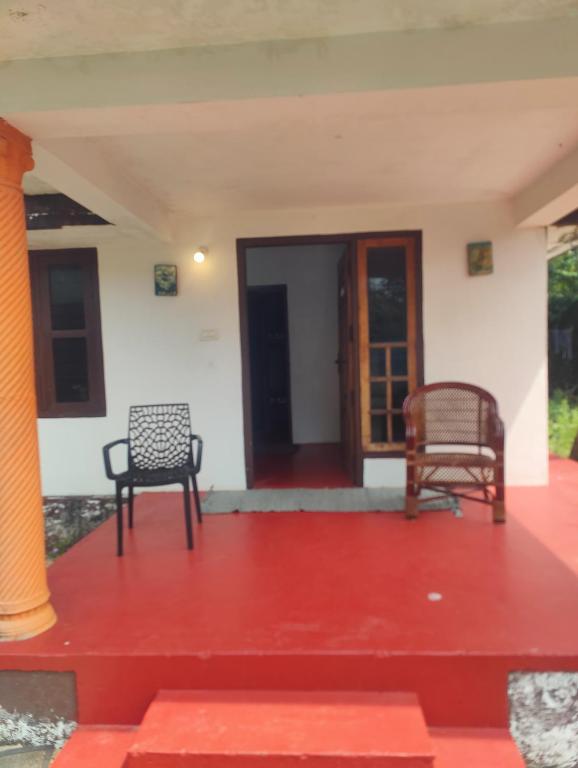 two chairs sitting on the porch of a house at Cuba beach villa in Alleppey