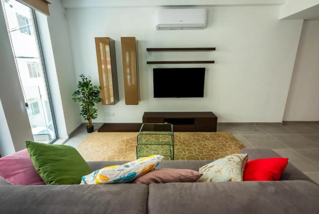 Una sala de estar con un sofá y un televisor de pantalla plana. en Elegant 2BR Seaside Stay, Balluta Bay Oasis P2, en Sliema