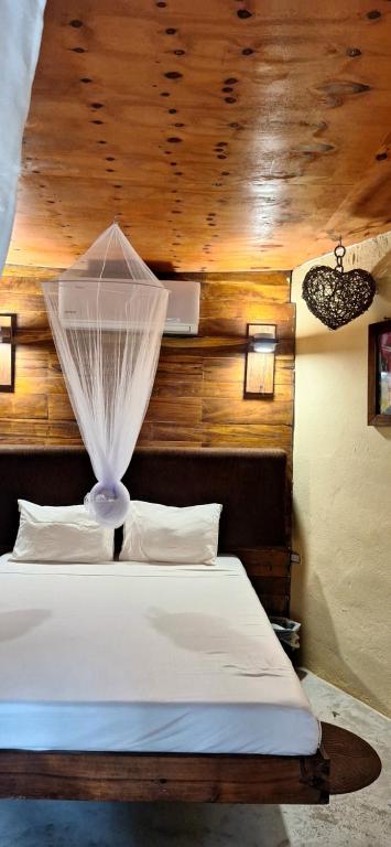 a bedroom with a white bed with a wooden ceiling at Las cabañas in Tulum