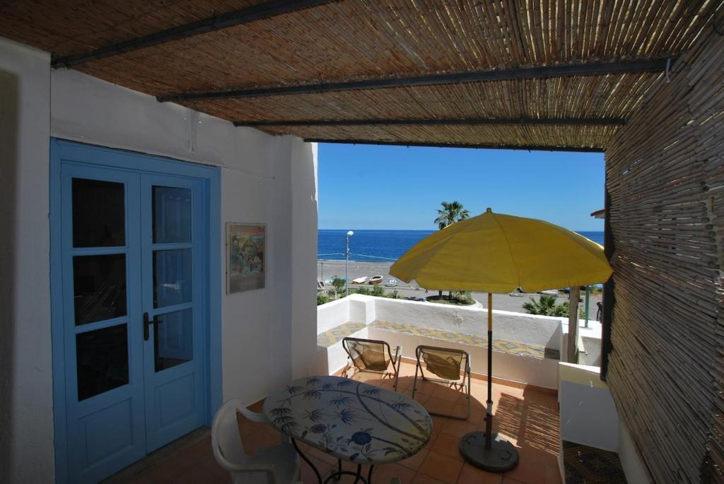 a patio with a table and chairs and a yellow umbrella at Zenzero canneto beach lipari in Canneto - Lipari