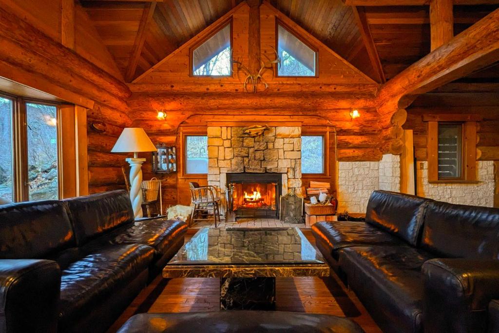 a living room with leather furniture and a fireplace at Hakuba Loghouse in Hakuba