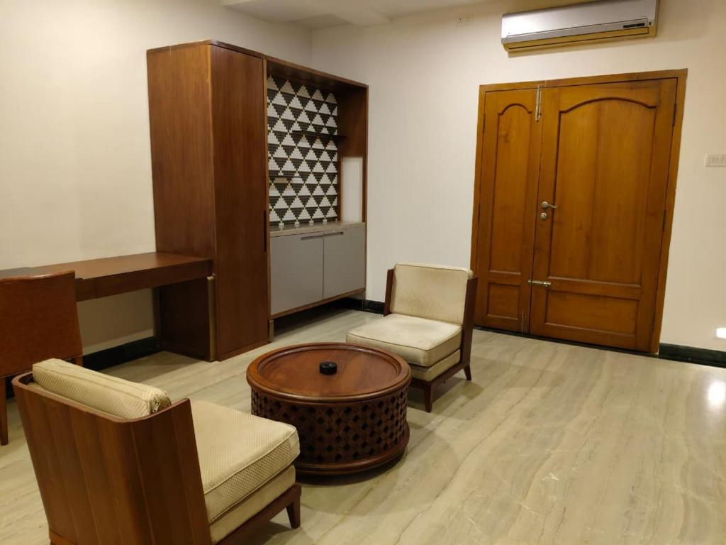 una stanza con sedie, tavolo e bottiglie di vino di Hotel Crossway a Chennai