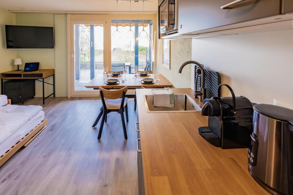 una cucina e un soggiorno con un tavolo e un letto di Surfers Oase near Interlaken at lake with pool a Därligen