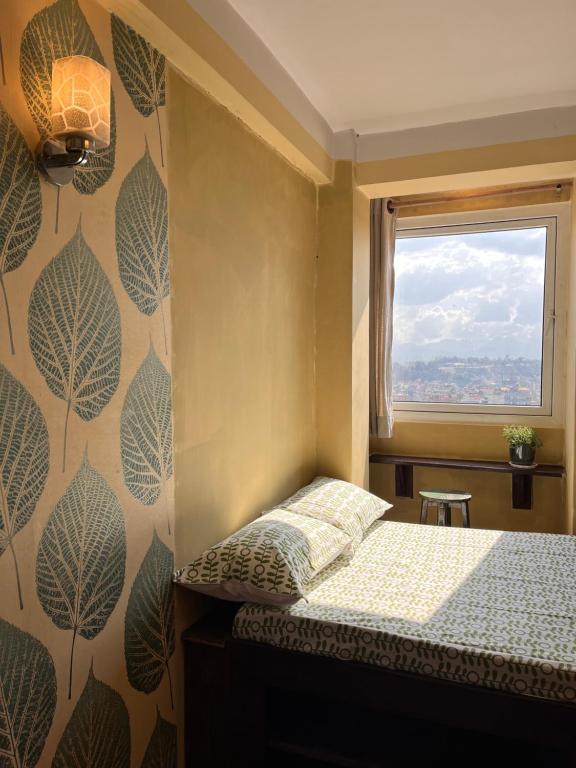 Rooftop apartment front Boudha View في كاتماندو: غرفة نوم صغيرة بها سرير ونافذة