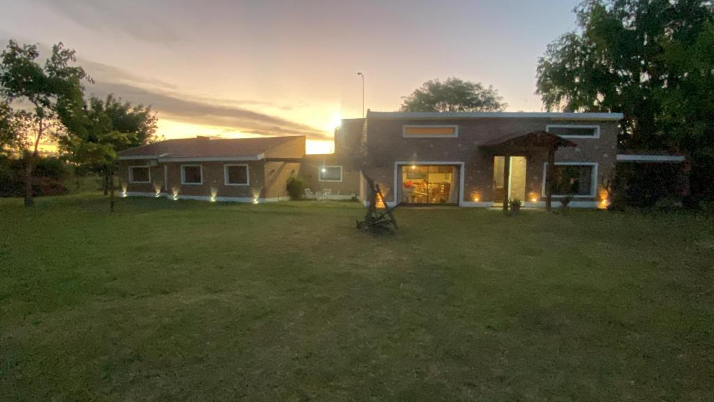 a house in a yard with the sun setting behind it at Casa de verano confortable in Villa Las Rosas