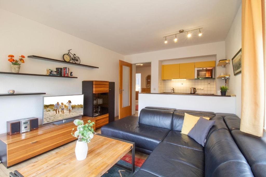 a living room with a black leather couch and a table at Brise Haus "Am Schloonsee" App 05 in Bansin