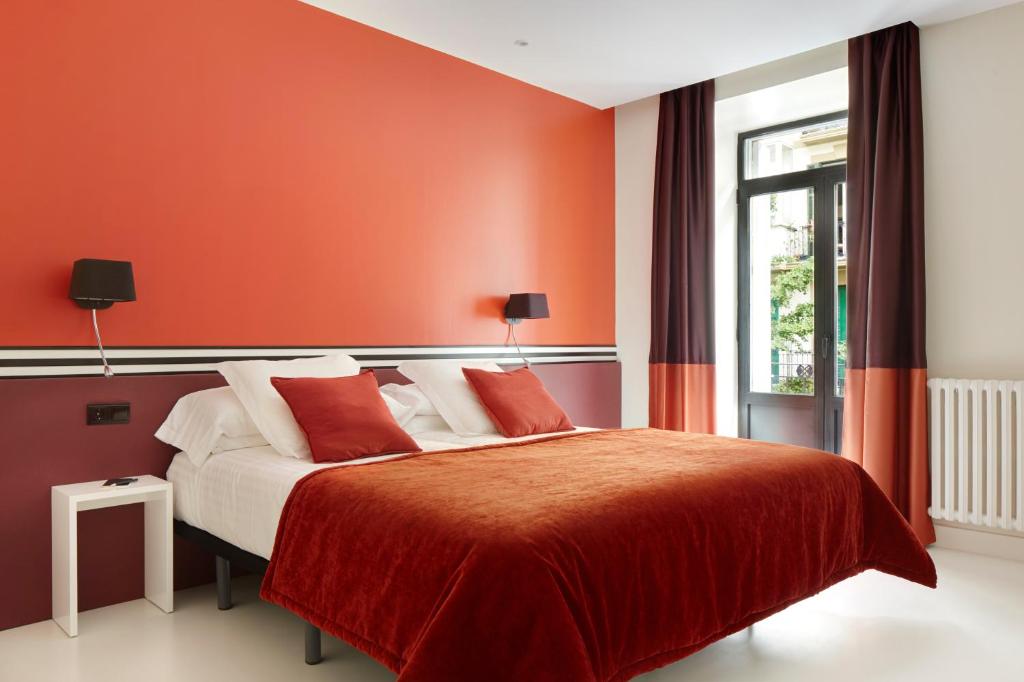 Schlafzimmer mit einem großen Bett mit roten Wänden in der Unterkunft Don Cecilio Guesthouse (Centro) in San Sebastián