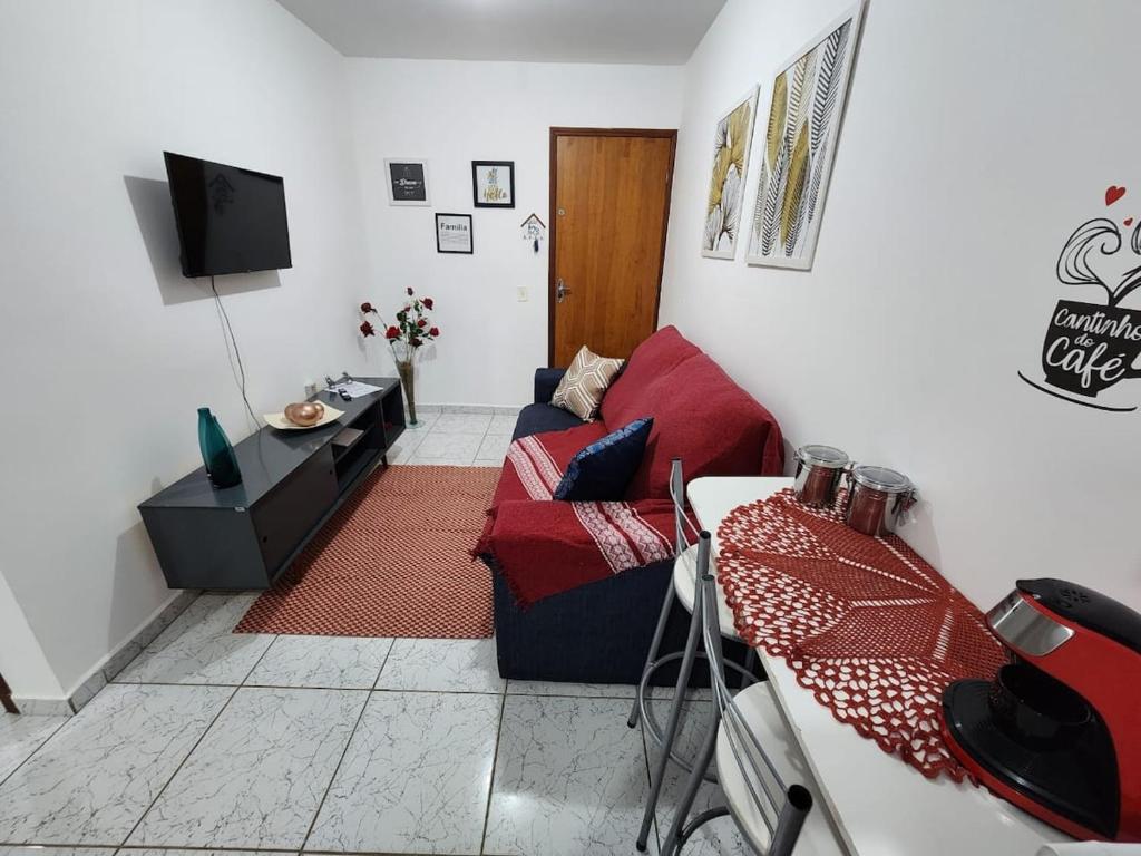 un soggiorno con un divano rosso e una TV di Apto 32. Lindo, aconchegante e completo. a Boituva